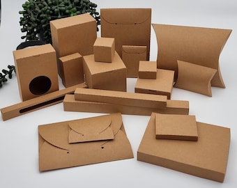 May include: Assortment of brown cardboard boxes in various shapes and sizes, including rectangular, square, and pillow-shaped boxes. The boxes are made of kraft paper and have a natural, rustic look.