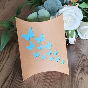 Può includere: Una scatola a cuscino marrone con un design a farfalla blu. Le farfalle sono disposte in diagonale, partendo dall'angolo in alto a sinistra e si estendono fino all'angolo in basso a destra.