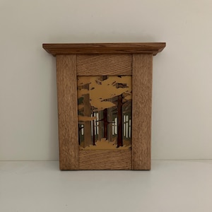 May include: A rectangular wooden wall hanging featuring a layered cutout design of a forest scene. The frame is constructed from light brown oak with a prominent grain. The interior depicts stylized trees in shades of tan, brown, and dark red.