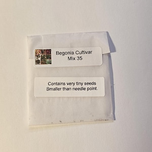 May include: A small white seed packet with the text "Begonia Cultivar Mix 35" and "Contains very tiny seeds Smaller than needle point." The packet has a small image of colorful flowers.