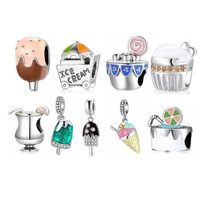 May include: A set of nine silver charm beads with various ice cream and dessert designs. The charms feature colorful enamel and glitter accents. The charms include an ice cream cone, a popsicle, a cupcake, an ice cream cart, a cocktail glass, and a cake.