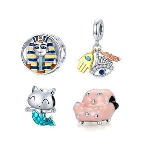 May include: Four silver charm beads with colorful enamel details. The first bead features a pharaoh with a yellow and blue patterned headdress. The second bead is a charm with a gold hand, a blue eye, and a feather. The third bead is a white cat with a turquoise mermaid tail. The fourth bead is a pink armchair with white dots.