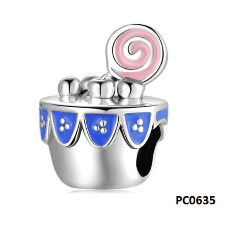 May include: Silver charm with a blue and white cake with a pink swirl lollipop on top. The charm has the code PC0635.