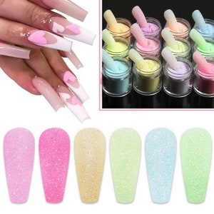 Puede incluir: Seis pequeños frascos de esmalte de uñas con purpurina de color pastel. La purpurina es una purpurina gruesa y texturizada. Los frascos son transparentes y la purpurina es visible en el interior.