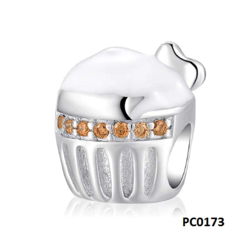 May include: Silver charm in the shape of a cupcake with white icing and brown crystal accents. The charm has a small heart on top and a textured base. PC0173