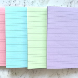 May include: Four lined notepads in different pastel colours: pink, light blue, light green, and lavender.