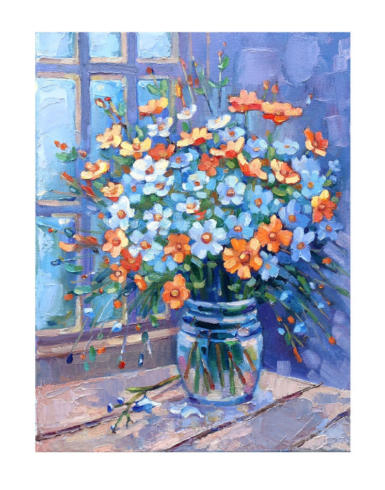 May include: A bouquet of blue and orange wildflowers in a clear glass vase on a wooden table. The flowers are arranged in a loose, natural style, and the vase is simple and elegant.