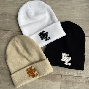 May include: Three knit beanies in white, beige, and black with a felt patch on each that says "KZ" in a varsity style font.