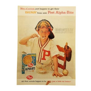 May include: A vintage advertisement for Post Alpha-Bits cereal featuring a young boy wearing a baseball uniform and catcher's mask, eating the cereal with a spoon. The ad text reads "Men of action just happen to get their ENERGY from new Post Alpha-Bits".