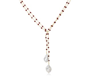 May include: A gold chain necklace with red beads and two large white pearl drops.