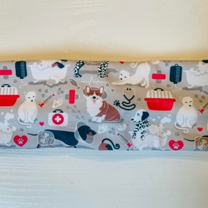 May include: A gray headband with a repeating pattern of dogs and cats in a veterinary theme. The pattern includes images of dogs and cats in a bathtub, a dog with a bandage, a cat in a carrier, and a first aid kit.