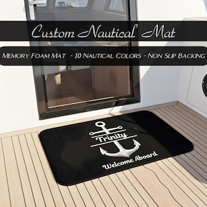 May include: Black rectangular nautical mat with a white anchor design and the name "Trinity". The mat also has the words "Welcome Aboard". The text "Custom Nautical Mat" is at the top.