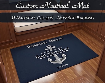 May include: A rectangular dark blue nautical mat featuring a silver anchor graphic in the center. The text reads Welcome Aboard, Boat Name Here, and Location. The mat has a non-slip backing and is designed for marine environments with custom text options.