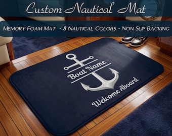 May include: A rectangular navy blue memory foam mat featuring a white graphic of a ship anchor. The text "Boat Name" is printed across the center of the anchor, and the words "Welcome Aboard" are printed in white below the anchor.
