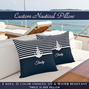 May include: Two navy and white striped nautical pillows with anchor designs and the name "Trinity". The pillows are on a white surface, with the text "Custom Nautical Pillow" at the top.