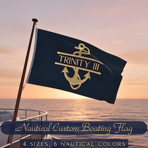 May include: A navy blue nautical flag with a gold anchor design and the text "TRINITY III". The flag is displayed on a wooden pole against a sunset backdrop. The text "Nautical Custom Boating Flag" is at the bottom.