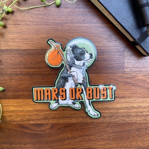 Puede incluir: Un perro blanco y negro con un casco espacial y llevando una pequeña bolsa naranja. El perro camina hacia el lado derecho de la imagen. El texto "Mars or Bust" está escrito en letras naranjas sobre un fondo verde.