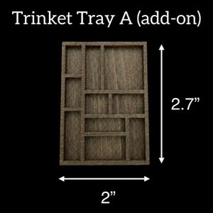 May include: Wooden trinket tray with multiple compartments. The tray is 2 inches wide and 2.7 inches tall. The text "Trinket Tray A (add-on)" is at the top. The tray is made of wood and has a dark brown color.
