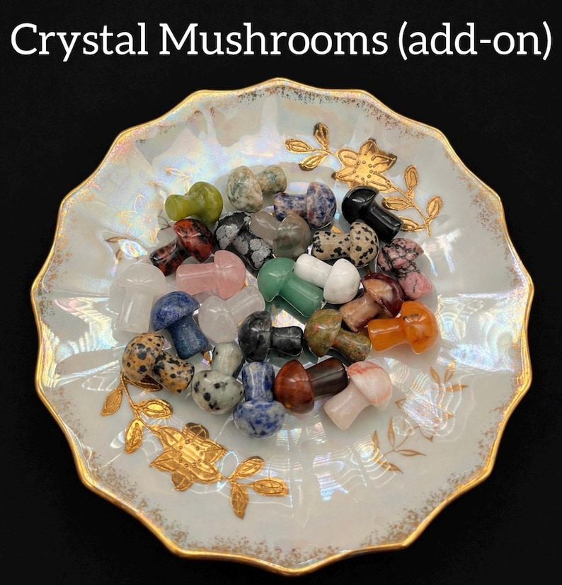 May include: A collection of crystal mushroom figurines in various colors, including green, pink, and black, are displayed in a decorative, gold-rimmed dish. The dish has a white and gold floral design. The text "Crystal Mushrooms (add-on)" is at the top.