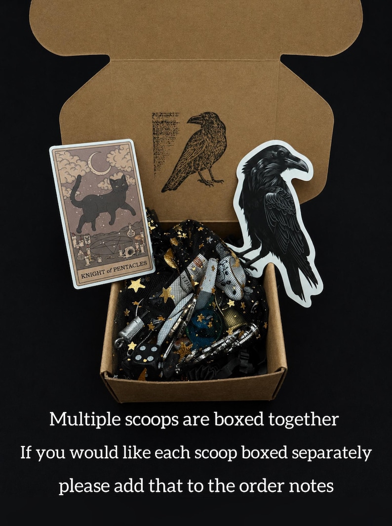 May include: A cardboard box containing a collection of items, including a tarot card with a black cat, stickers of ravens, and various small objects. The box is lined with black fabric with gold stars. Text on the image reads: "Multiple scoops are boxed together."