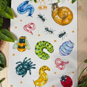 Puede incluir: Una hoja de pegatinas con ilustraciones coloridas de varios insectos y criaturas. Incluye una serpiente azul, un caracol, hormigas, un gusano, una abeja, una oruga, una araña, una babosa, un capullo y una mariquita. Contiene el texto "MAL.INKY".