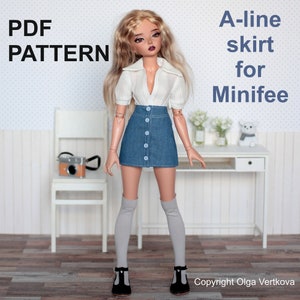 Peut inclure: Patron PDF pour une jupe trapèze pour une poupée Minifee. La jupe est en jean bleu avec un devant boutonné et la poupée porte un pull blanc.