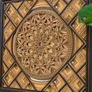 May include: A square wooden wall art piece with a geometric design in shades of brown, orange, and yellow. The design features a central circle with intricate patterns and layered squares around it.