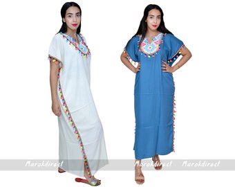 May include: Two long, flowing dresses. One is white, the other is blue. Both have colorful embroidered necklines and sleeves, and are trimmed with tassels. The dresses are floor-length and have short sleeves. The text "Marokdirect" is at the bottom.