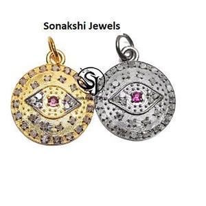 May include: Two round pendants with an eye design. One pendant is gold-toned with a red center and the other is silver-toned with a red center. The pendants are embellished with small stones. The text "Sonakshi Jewels" is at the top.