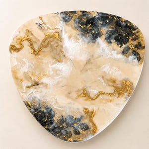 Pode incluir: Uma bandeja decorativa, de formato triangular, com base creme, adornada com detalhes dourados e padrões florais azul escuro. A bandeja apresenta um efeito marmorizado, aumentando o seu apelo artístico.