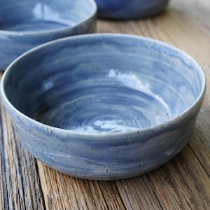 Può includere: Tre ciotole in ceramica blu con un motivo a spirale. Le ciotole sono su una superficie di legno.