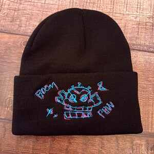 May include: Black beanie with a blue and pink embroidered design of a robot face with the text "BOOM X POW" on the front.