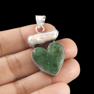 May include: A silver pendant featuring a green heart-shaped stone and a white baroque pearl. The pendant is designed with a silver bail for attaching to a chain.