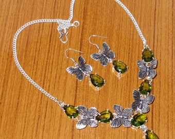 May include: A silver necklace and earrings set with green gemstone accents and butterfly designs.
