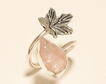May include: A silver ring with a pink rose quartz stone and a silver maple leaf design.