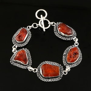 May include: A silver bracelet with five orange carnelian stones set in ornate silver frames. The bracelet has a toggle clasp.