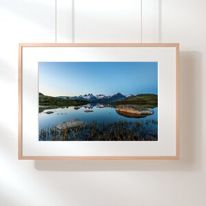May include: A framed photograph of a mountain lake reflecting the surrounding peaks. The water is still and the sky is a light blue.