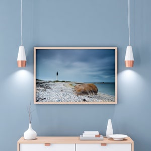 Fotografía de una playa de guijarros y el faro Ile de Sein en Bretaña