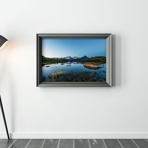 May include: A framed photograph of a mountain range reflected in a still lake. The mountains are snow-capped and the lake is a deep blue. The photo is in a black frame.
