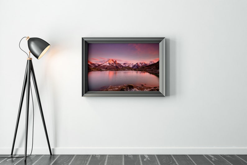 May include: A framed photograph of a mountain lake with snow-capped peaks reflecting in the water at sunset. The sky is a vibrant purple and pink.