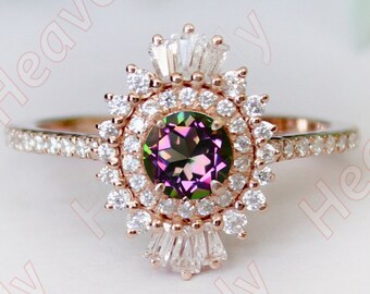 Puede incluir: Un anillo de oro rosa con una piedra preciosa redonda multicolor rodeada por un halo de diamantes más pequeños. El anillo tiene una banda delicada con diamantes más pequeños.