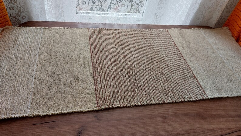 Peut inclure: Un chemin de table tiss&eacute; compos&eacute; de trois sections. La section centrale est de couleur brun fonc&eacute;, tandis que les deux sections ext&eacute;rieures sont de couleur beige clair.