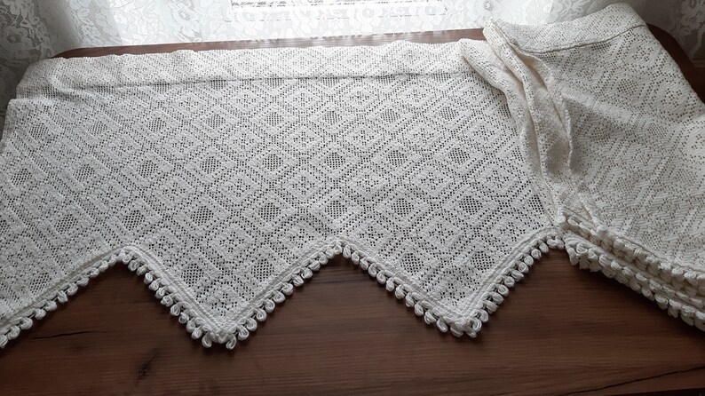 May include: White crocheted valance with a diamond pattern and a scalloped edge with tassels.