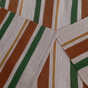 May include: A striped rug with brown, green and gold stripes on a white background.