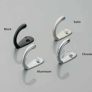 May include: Four metal wall hooks with curved designs and two screw holes on the base. The finishes are labeled as Black, Satin, Aluminum, and Chrome. Each hook features a smooth, rounded top and a flat mounting plate for secure installation.
