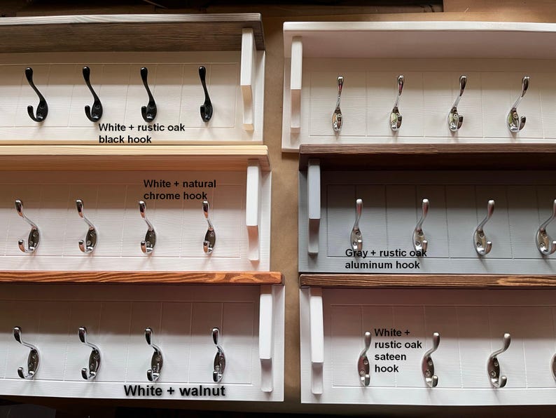 May include: Five different styles of white wooden coat racks with five hooks each. The racks have different wood finishes and hook colors. The finishes are white with rustic oak, white with natural chrome, gray with rustic oak, white with walnut, and white with rustic oak sateen. The hooks are black, chrome, aluminum, and silver.