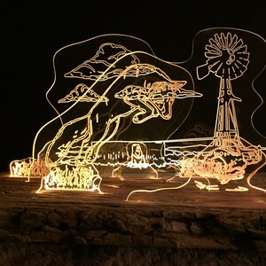 May include: A laser-cut acrylic art piece depicting a horse jumping over a fence with a windmill in the background. The piece is illuminated from behind, creating a glowing effect.
