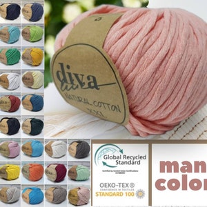 Könnte beinhalten: Ein großer Knäuel rosa Diva Natural Cotton XXL Garn mit braunem Etikett. Das Bild zeigt eine Vielzahl von Garnfarben, darunter Blau, Grün, Gelb und Grau. Der Text "many colors" ist sichtbar. Das Garn ist vom Global Recycled Standard und Oeko-Tex zertifiziert.