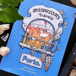 May include: A blue coloring book titled Mushroom's Travels Porto by Maryna Kostiushko. The cover features an illustration of a character and a seagull on a balcony with a sunset background, framed by decorative vines and architectural elements.