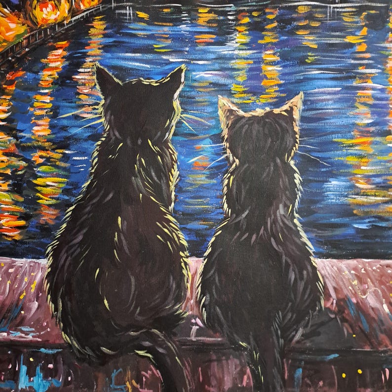 May include: Two black cats sit side-by-side on a ledge, looking out at a body of water with shimmering lights reflecting on the surface.